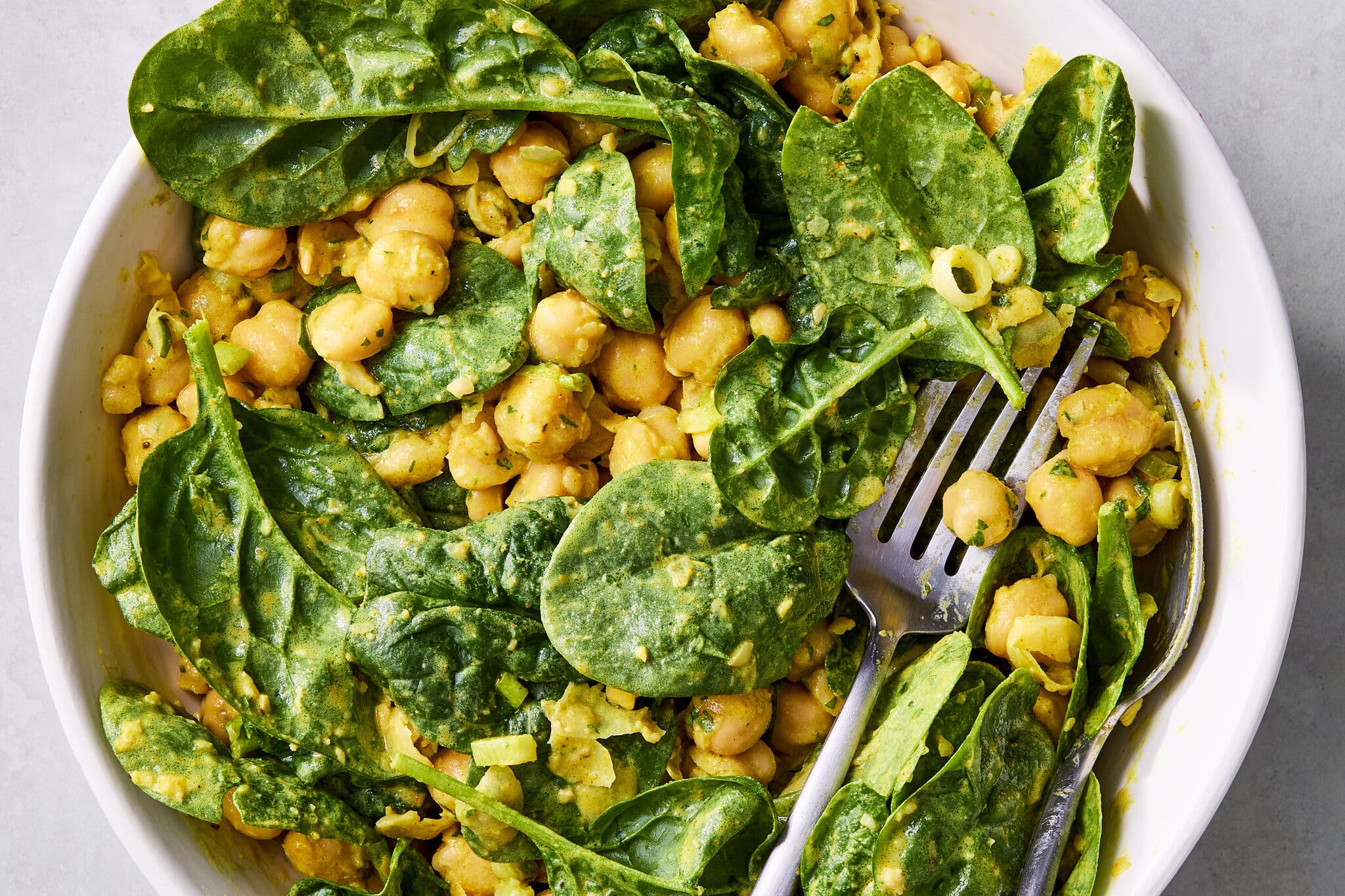 Curried chickpea and spinach salad in a white bowl.