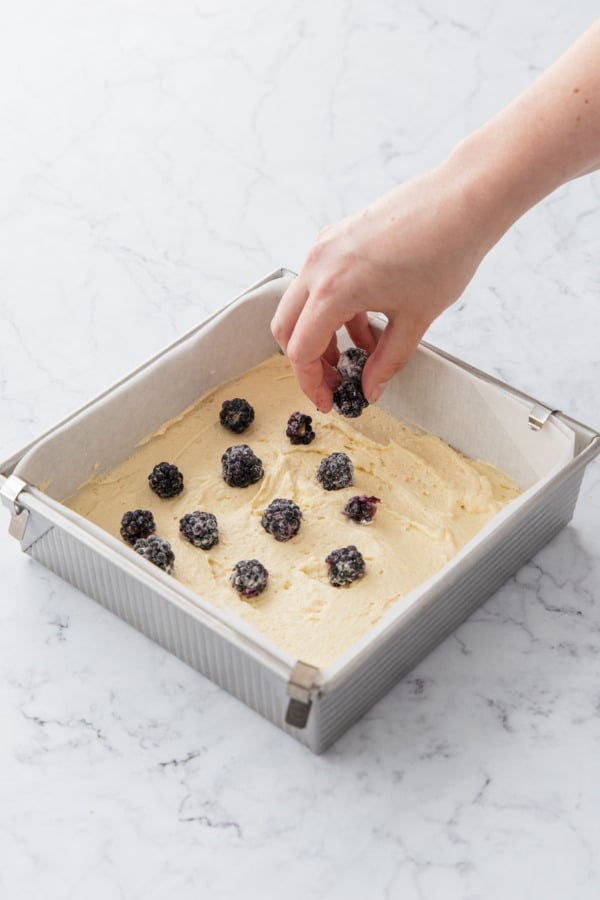 Placing flour-dusted blackberries on top of first layer of cake batter.