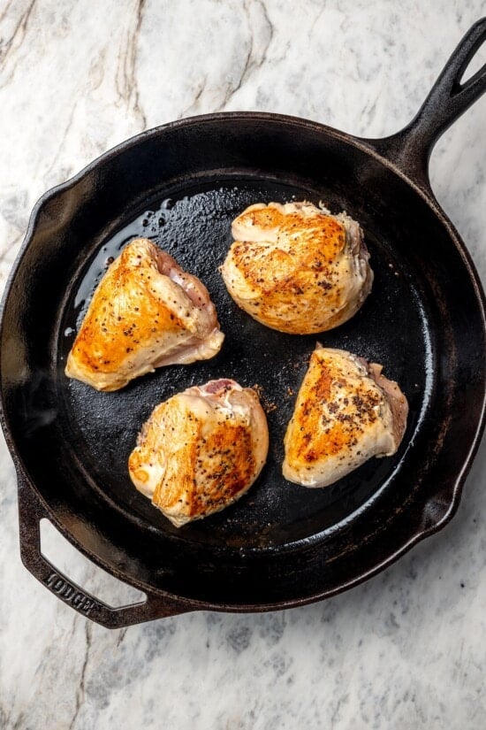 Cauliflower and chicken breasts make this Chicken Scarpariello recipe low carb, but it's just as spicy and flavorful as the classic version! Chicken breast halves browning in cast iron skillet.