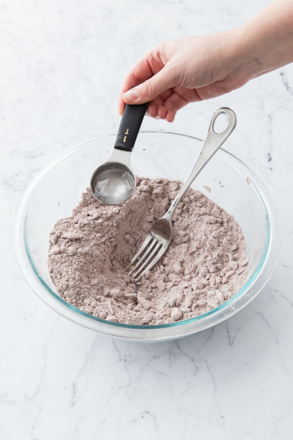 Drizzing ice water into a well in the middle of the blended pie crust mixture.