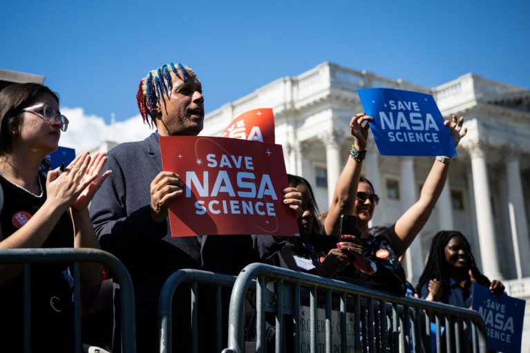 Demonstrators hold signs during a news conference on NASA funding at the US Capitol in Washington DC.