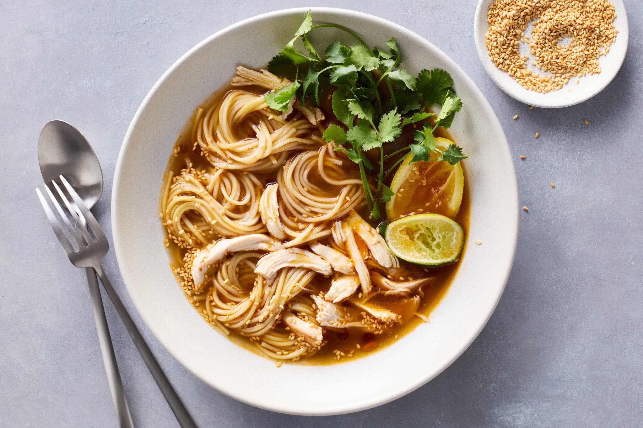 An overhead image of a brothy bowl of noodles and chicken.