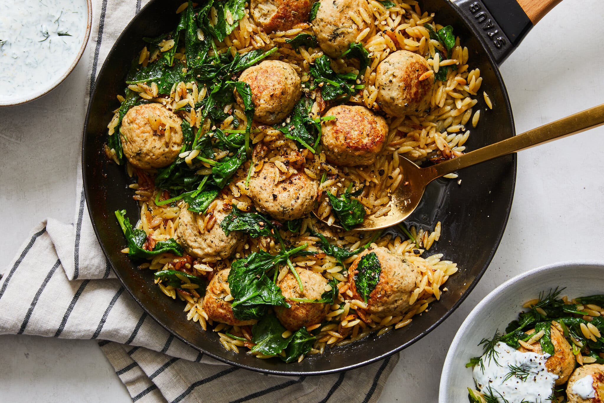 An overhead image of meatballs and orzo in a skillet.